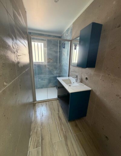 Création d’une salle de bains sur mesure Salle de bains rénovée avec meuble vasque, douche et revêtements muraux contemporains