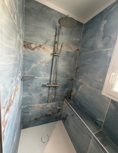 Pose de douche à l’italienne par Nicolas Dupuet Installation d’une douche à l’italienne avec carrelage mural effet pierre dans une salle de bains rénovée